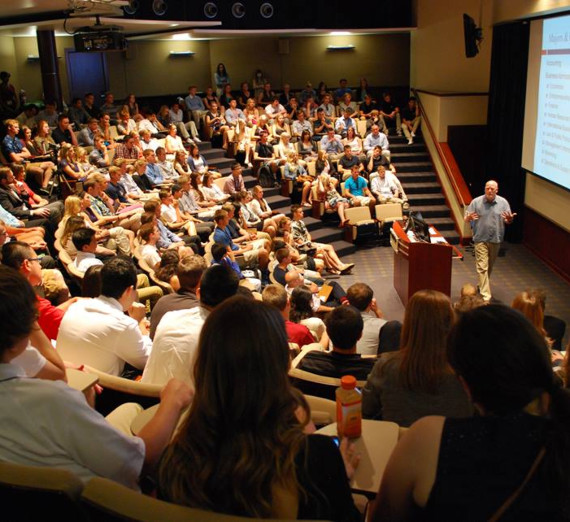 A woman with blond hair hands a Christmas stocking to a woman with long brown hair